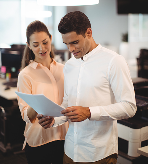 Employee reading a paper while another employee looks on