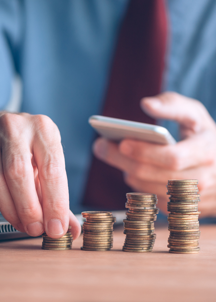 Hands stacking coins and holding a phone